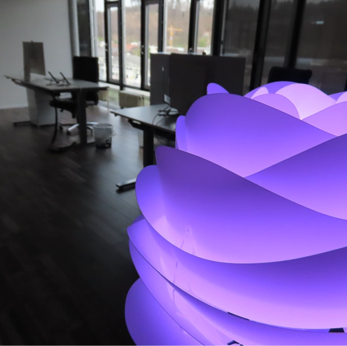 Modernes Büro von Swisscare Switzerland AG in Bern mit Schreibtischen und stilvoller lila Stehlampe in Blumenform Innenaufnahme eines modernen Büros mit Schreibtischen und einer lila Stehlampe in Blumenform bei Swisscare Switzerland AG in Bern